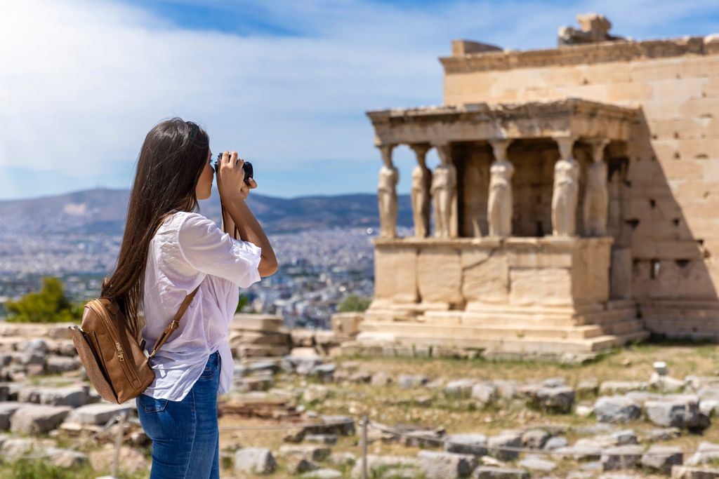 A female tourist takes pictures of the Erechtheion Temple at the Acropolis of Athens, Greece, during her summer vacations