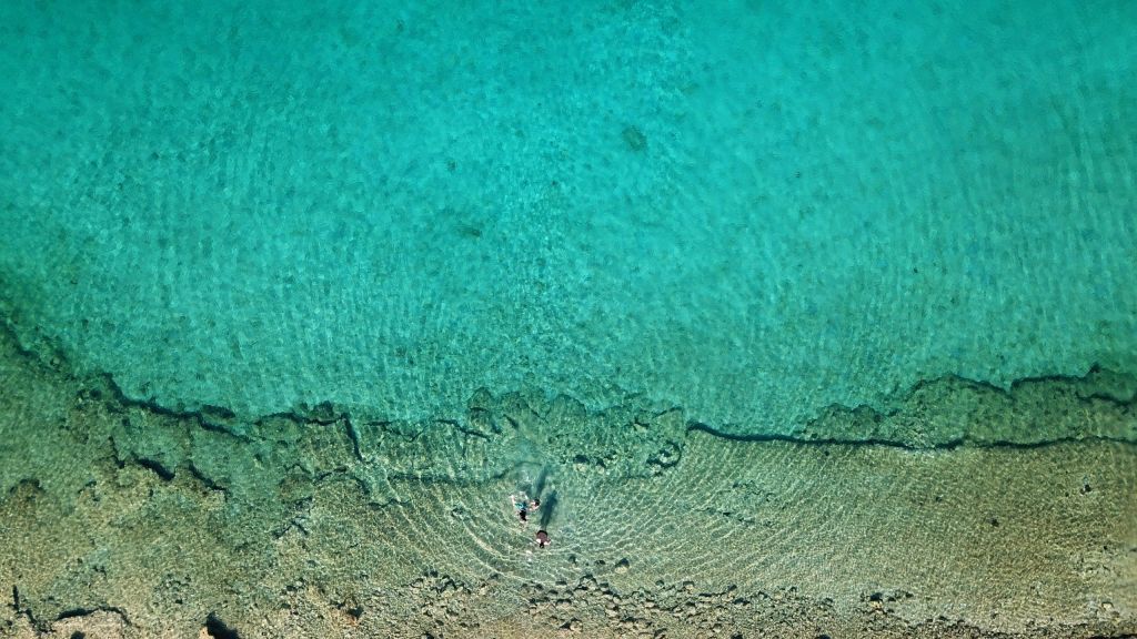 Aerial drone bird’s eye view photo from turquoise clear water seascape in island of Shinousa or Schinoussa, Cyclades, Greece