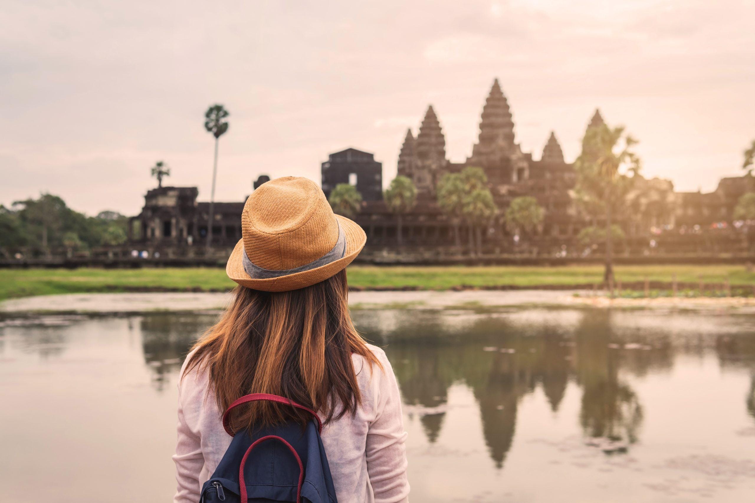 Young woman traveler looking at Angkor Wat, Khmer architecture heritage in Siem Reap, Cambodia
