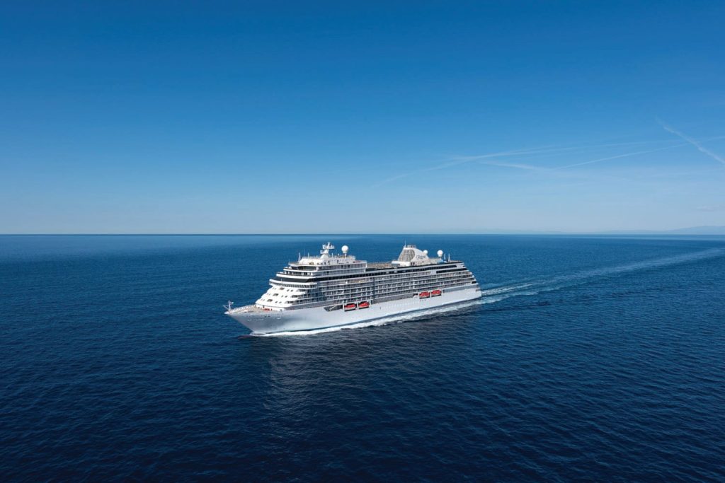 Cruise ship sailing across calm blue sea under a clear sky.