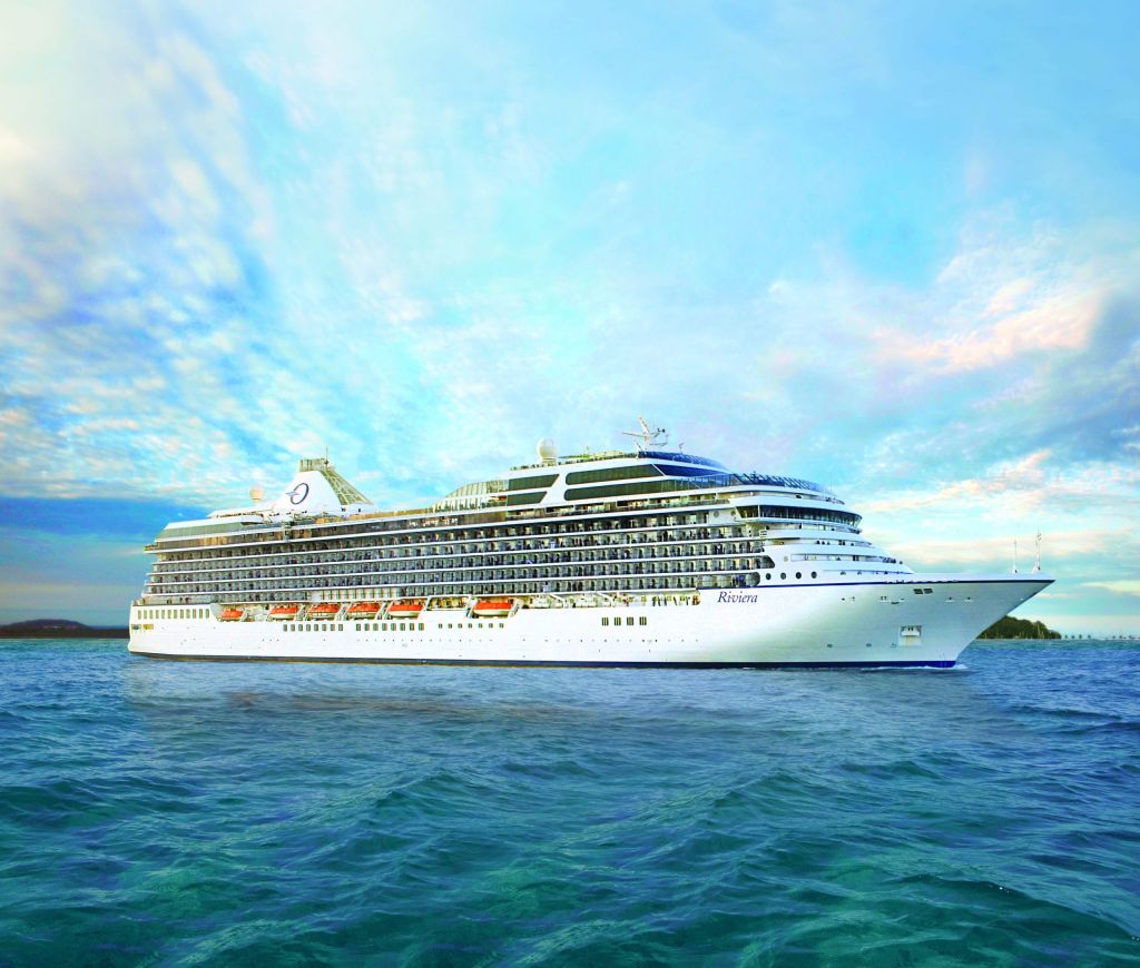 White cruise ship named Riviera sailing on turquoise water under a cloudy sky.