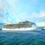 White cruise ship named Riviera sailing on turquoise water under a cloudy sky.