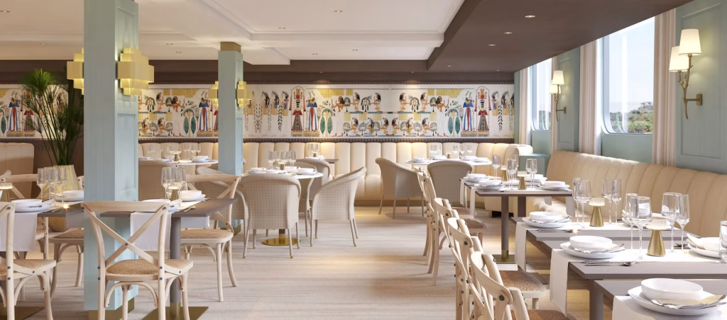 Elegant dining room with cream booths, wood tables, and gold-accent decor; a long mural spans the back wall under soft lighting