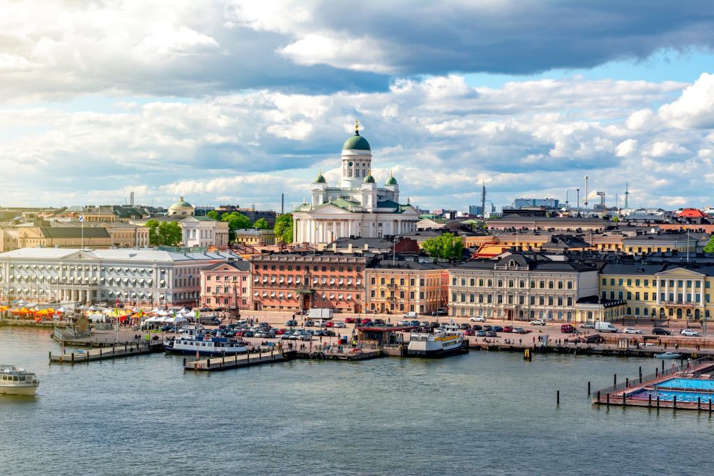 Helsinki waterfront with a green-domed cathedral, harbour boats and a city of pastel buildings.