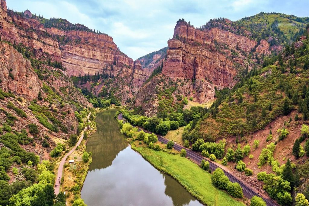 Red rock canyon with a winding river and a highway running along its banks.