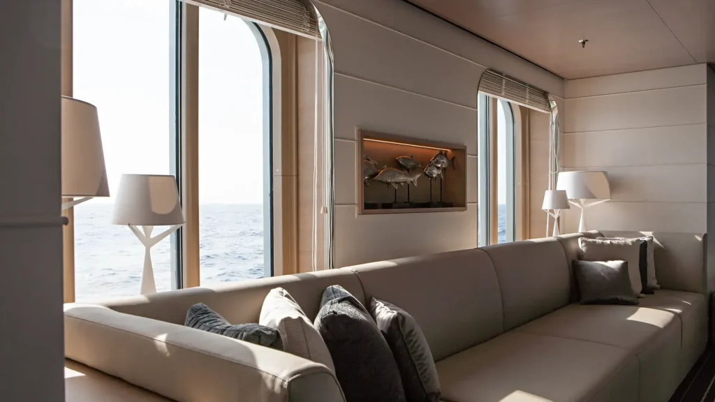 Lounge suite with a cream sofa, lamps and arched windows overlooking the sea.