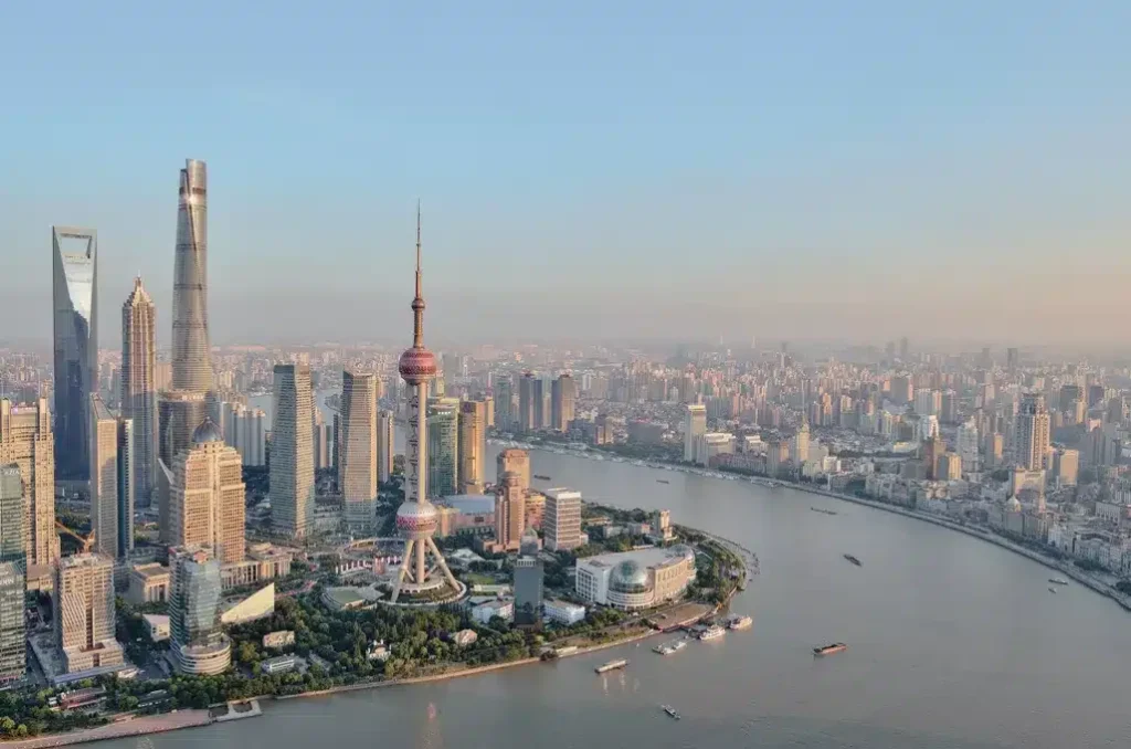 Aerial view of Shanghai skyline along the Huangpu River, with the Oriental Pearl Tower and modern skyscrapers in Pudong.