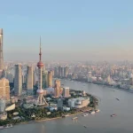 Aerial view of Shanghai skyline along the Huangpu River, with the Oriental Pearl Tower and modern skyscrapers in Pudong.