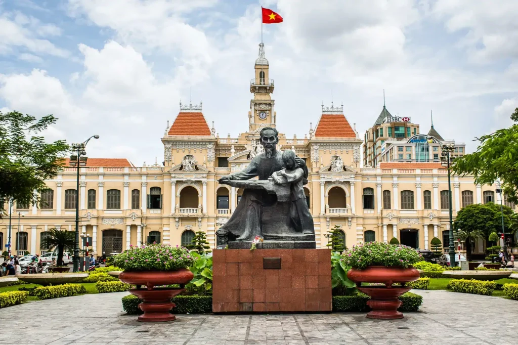 Yellow colonial-style city hall with a bronze statue of a man and child in front.