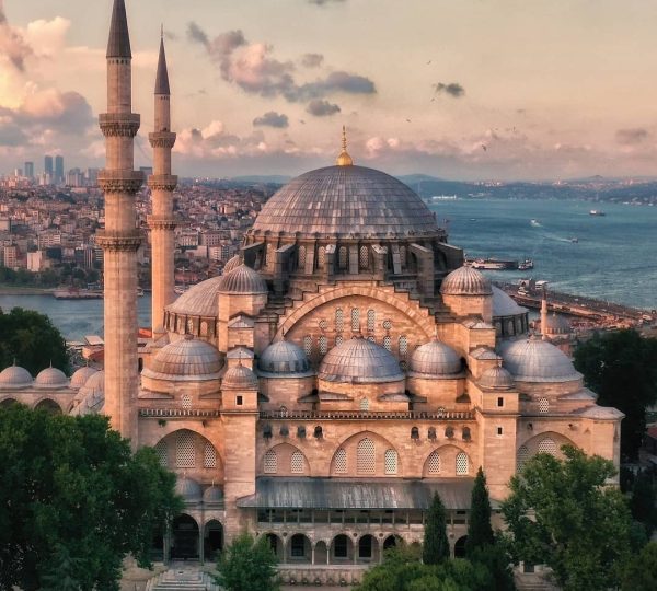 Visit Turkey and Sultan Ahmed/Suleymaniye Mosque with tall minarets overlooking the Bosphorus and a cityscape at sunset