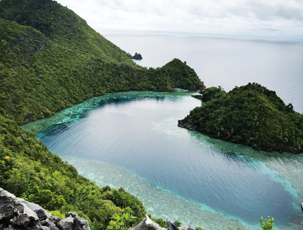 Tropical bay with green cliffs, clear turquoise water, and a rocky shoreline