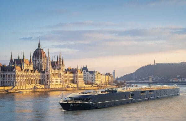 Budapest Parliament building along the Danube with a modern black cruise ship on the water at sunset