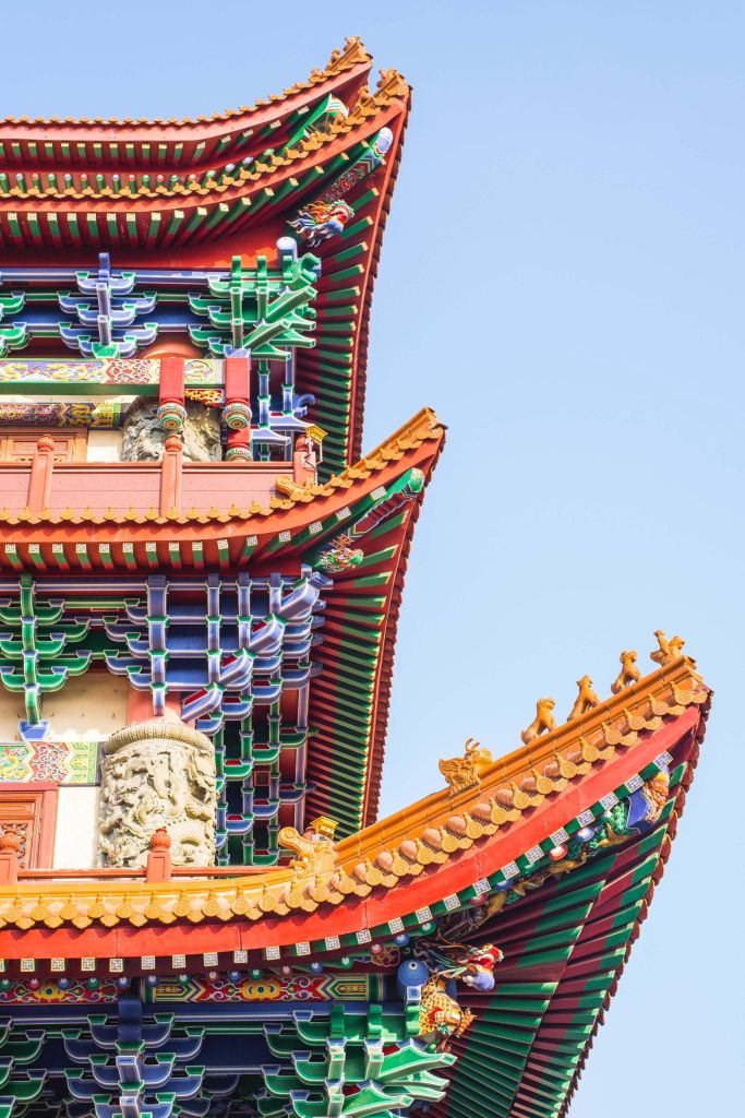 Colorful traditional Chinese temple roof with layered eaves and dragon motifs against a blue sky